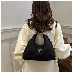 Detail of black nylon hobo bag showing the metallic triangular logo and crossbody strap
