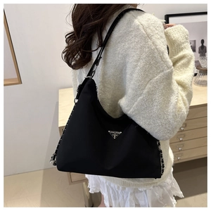 Back view of a large black nylon tote bag with silver chain and metal plate on shoulder