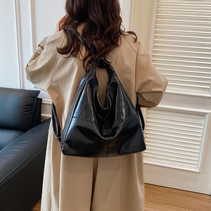Minimalist black glossy leather hobo tote bag for women shown in a lifestyle setting