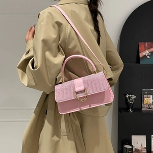 Sac à bandoulière rose avec strass brillants et boucle dorée porté par un mannequin