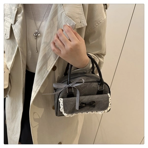 Detail of grey fabric Boston bag with lace trim and decorative bows held by a model
