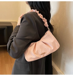Dettaglio borsa in velluto rosa plissettato con logo metallico e manico arricciato