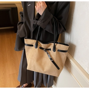 Detail of a large sand suede tote bag with black leather handles for stylish commuting