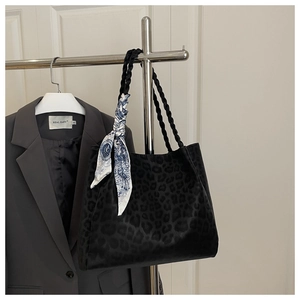 Detail of leopard print tote bag with woven handles and a decorative silk scarf