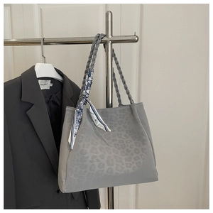 Detail of light gray leopard print tote bag with woven handles and floral scarf detail