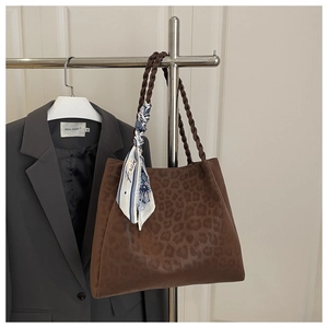 Detail of leopard print tote bag with woven handles and decorative blue printed silk scarf