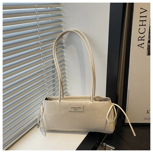 Detail view of cream tote bag featuring side drawstring bows and logo patch texture
