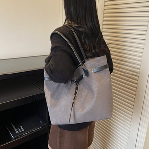 Large gray suede tote bag with black leather straps and metal buckle shown on a model