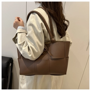 Détail d'un sac cabas tressé marron café montrant l'artisanat et la texture du cuir premium