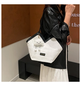 White corduroy handbag with V-shaped opening and cloud charm shown on model shoulder