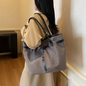 Large taupe suede tote bag with black leather handles and buckle detail on shoulder