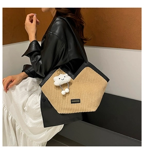 Detail of beige corduroy shoulder bag with black trim and a white cloud charm