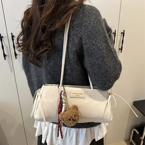 Retro white leather tote bag with bear charm worn by a model in a minimalist setting