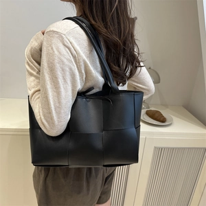 Grand sac cabas tressé noir minimaliste pour femme porté à l'épaule au style moderne