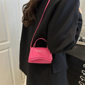 Pink patent leather hourglass handbag with curved flap design and shoulder strap