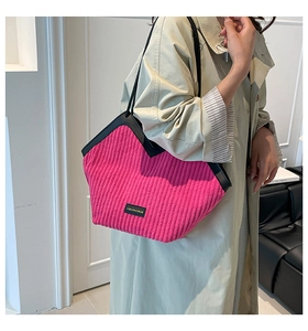 Close-up of pink corduroy tote bag with black leather handles and fashion logo tag