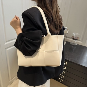 Sac fourre-tout chic en cuir tressé beige montré de profil par un mannequin femme