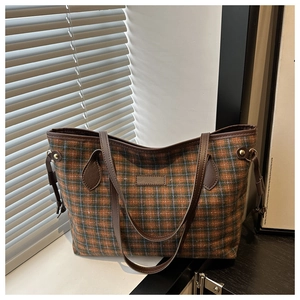 Detail of British style checkered tote bag with tweed texture and brown leather straps