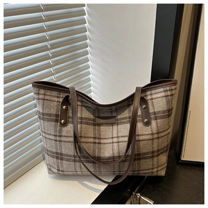 Close-up of classic plaid pattern tote bag with leather handles and metallic rivets