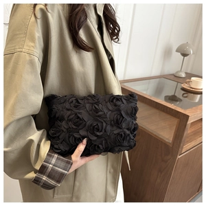 Detailed view of a black evening clutch with handcrafted 3D mesh rose petals and metal zipper