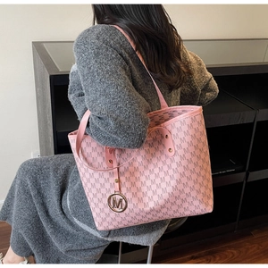 Détail du sac cabas rose avec motif monogramme M et pendentif métallique doré rond