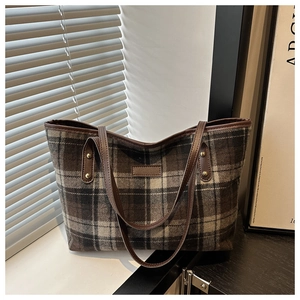 Detail view of plaid tote bag featuring woolen fabric texture and brown leather trim