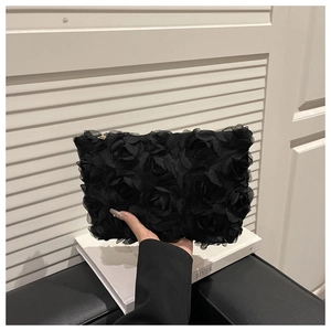Detail of 3D rose floral texture on a black evening clutch bag with gold zipper