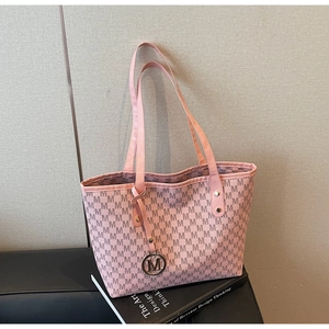 Détail du sac cabas rose avec imprimé à motif M et pendentif logo en métal rond