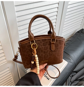 Gros plan du sac à main imprimé léopard avec anses en cuir et pendentif décoratif en perles