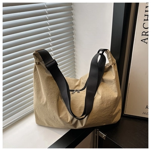 Close-up of khaki nylon pillow bag with black adjustable strap and zipper detail