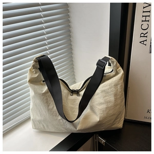 Detail of off-white nylon pillow bag with wide black strap and dual zipper closure