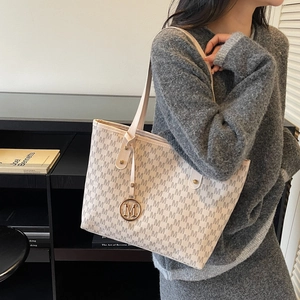 Sac fourre-tout vintage à motif M et pendentif doré porté à l'épaule