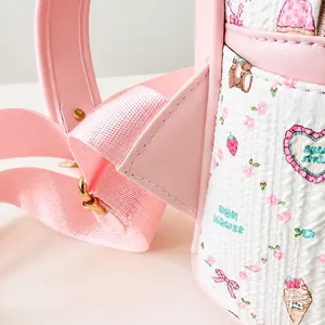 Détail de couture triangulaire renforcée et bandoulière rose sur sac à dos matelassé