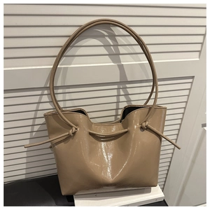 Close-up of warm brown patent leather tote bag with drawstrings and glossy finish