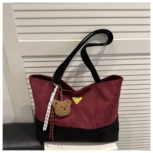 Detalle del bolso tote burdeos y negro con logo metálico y colgante de osito peluche