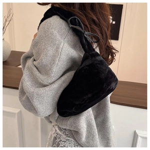 Detail of black faux fur shoulder bag with soft plush strap and elegant ribbon bow accent