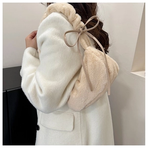 Detail of soft beige faux fur shoulder bag featuring decorative ribbon bow accents