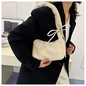 Detail of cream faux fur shoulder bag featuring decorative bow side ties and plush texture