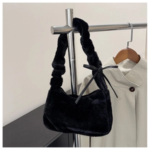 Detail of black faux fur underarm bag featuring a delicate leather bow and plush texture
