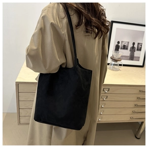Dettaglio della borsa tote in pelle scamosciata nera portata sopra un trench chic