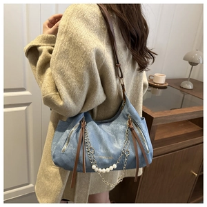 Détail du sac hobo bleu clair avec chaînes dorées et perles sur un manteau en laine
