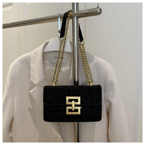 Detail of black leopard print suede crossbody bag with gold hardware and chain strap