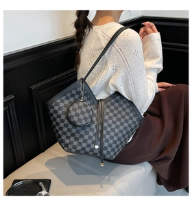 Detail of checkered tote bag and round coin purse charm worn on model's shoulder