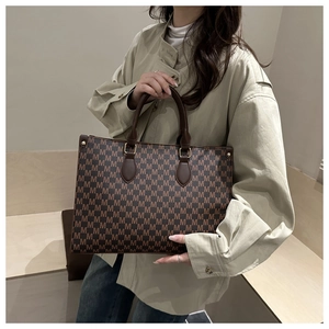 Detailed view of a vintage monogram tote bag with gold hardware and top handle strap