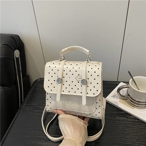 Weißer Polka-Dot Rucksack mit schwarzen Punkten und Tragegriff auf Holztisch
