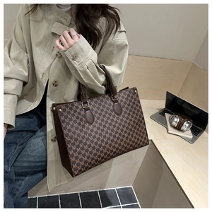 Detail of vintage monogram tote bag with brown leather handles in a chic office setting