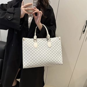 Minimalist large tote bag with M-letter monogram print carried by a model in a black coat