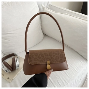 Detail of vintage leopard print flap and gold snap button on a brown leather shoulder bag