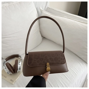 Detail of a brown leather shoulder bag with leopard print flap and gold vintage buckle