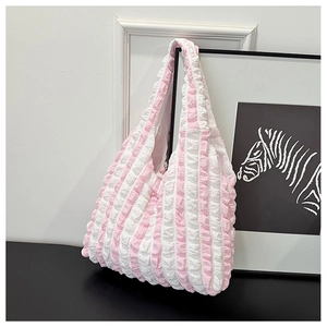 Detailed view of pink and white striped pleated canvas shoulder bag on a stylish display